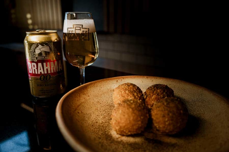 Imagem mostra um prato de bolinho de macaxeira pubada harmonizado com cerveja zero